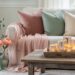Coastal living room scene with sheer blush fabric, glowing mercury glass votives on a weathered wood tray, velvet cushions, and fresh flowers with eucalyptus.