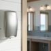 Sleek modern commercial hand dryer mounted in a Southern coastal bathroom with light shiplap walls, natural wood accents, and soft blue-gray tiles.