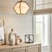 Sculptural matte ceramic decor and brushed brass accents styled on a console table in a bright modern Southern living room with geometric pendant lighting and natural linen window shades.
