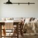 Cozy living room with weathered wood farmhouse table, patchwork quilt, white shiplap wall, and black metal accents in soft natural light.