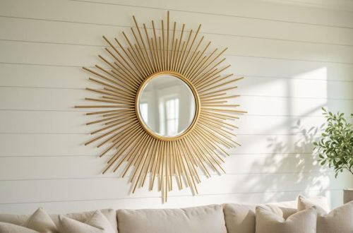 Gold sunburst mirror with radiating metal rays mounted on a whitewashed wall in a bright Southern coastal living room.